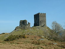 upon a grassy hillock stands two rectangular built fortifications. The one to the left is ruinous whilst the one to the right appears whole with battlements