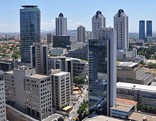 A half dozen skyscrapers interspersed among low- and mid-rises, with open expanse visible in the background
