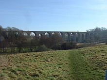 stone viaduct with multiple arches, partly obscured by tress
