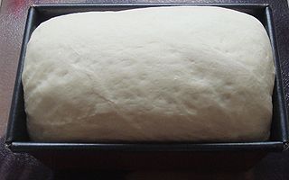 Risen bread dough in tin.jpg