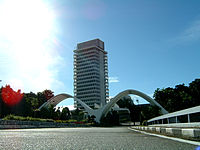 A photo showing the Malaysian Parliament building along with two white arches in diagonal position front of the building.