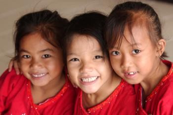 Three girls in red tops smiling, Thailand