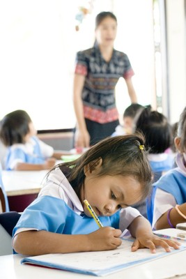 A girl at school in Thailand, with her teacher behind her