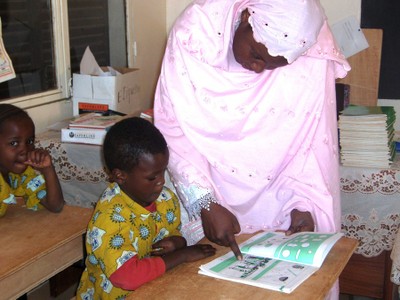 Teacher helping child in school, Niger