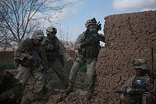 Los soldados al lado de una pared de barro