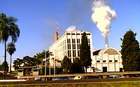 Foto del edificio de menor con humo saliendo de la chimenea junto a cinco pisos del edificio de oficinas
