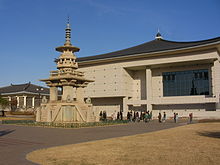 Un modelo de una pagoda de piedra de la izquierda y un edificio de marfil con un techo de color azul oscuro cursiva en el fondo