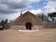 Fotografía del palacio del rey en Nyanza, Ruanda que representa la entrada principal, frente y techo cónico