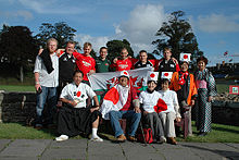 Un grupo de trece partidarios presentan juntos, algunos jerseys de rugby que llevaba mientras que otros deporte trajes tradicionales japoneses y banderas japonesas.