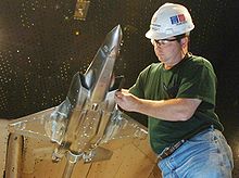 Ingeniero manejo de un modelo metálico escala del avión de combate en el túnel de viento