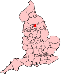 Un mapa de Inglaterra de color rosa que muestra las subdivisiones administrativas del país. La zona de ciudad metropolitana de Leeds es de color rojo.