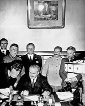 El ministro de Asuntos Exteriores soviético Vyacheslav Molotov firma el Pacto Molotov-Ribbentrop. Detrás de él de pie ministro de Exteriores alemán Joachim von Ribbentrop y el primer ministro soviético Joseph Stalin.