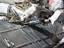 Un astronauta utiliza un destornillador para activar un puerto de acoplamiento en un módulo de la ISS.