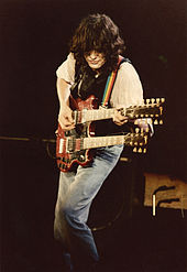 Una fotografía en colores de Jimmy Page actuando en el escenario con una guitarra de doble cuello