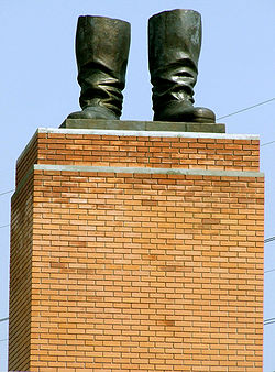 un pedestal de ladrillo bronceado que soporta un par de botas de la estatua de bronce con nada conectado