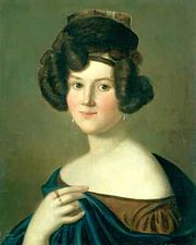 La tête et le torse d'une jeune femme blanche aux cheveux noirs fait dans un style élaboré. Elle porte un petit chapeau, un manteau et robe qui expose ses épaules et boucles d'oreilles. Sur sa main gauche qui tient le bord du manteau, deux anneaux sont visibles.