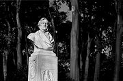 Un buste blanc sur un stand place qui porte le nom de Wagner. Il ya des arbres derrière elle.