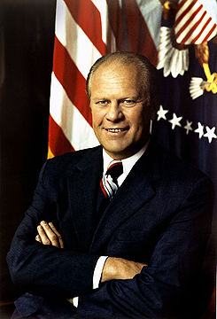 Président Gerald Ford, les bras croisés, devant un drapeau des États-Unis et le sceau présidentiel.
