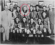 Deux hommes en costume et un autre homme dans un uniforme scout garçon debout près de 10 garçons adolescents assis en uniformes scouts. Ford est indiquée par un cercle rouge.