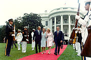 Deux couples de marche sur un tapis rouge, loin de la Maison Blanche. Garde d'honneur militaire de tous les services se mettre au garde le long des deux côtés du tapis.