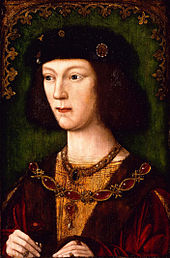 Un jeune homme avec de longs cheveux noirs et un teint clair. Il porte un chapeau et des vêtements doublé de fourrure ornée de bijoux et tenant une rose rouge dans sa main droite.