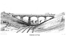 Un pont sur chevalets sur quatre piliers se étend sur une coupe sur deux voies ferrées