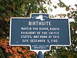 Un marqueur de bronze avec une carte de l'État de New York au sommet, sous laquelle se trouve le mot Birthsite et autre texte