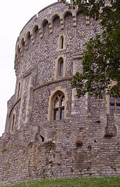 Une photographie montrant le côté gauche d'une tour de pierre circulaire en pierre grise et avec de petites fenêtres.