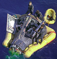 Photo de Armstrong et Scott dans la capsule Gemini, dans l'eau. Ils sont assistés par une certaine équipe de récupération