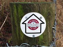 Poteau en bois avec Waymarker circulaire montrant une flèche contenant le logo de Butcombe Brewery