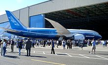 Grande porte de l'usine salle Everett se ouvre comme la première 787 est déployé. Entourant l'aéronef sont invités et le public.