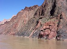 Rocher gris et rougeâtre surface rugueuse adjacente à une rivière.
