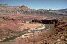 Rocher brun foncé couches dans le modèle stairstep dans corniches au-dessus d'une rivière dans un canyon de rouge et de la roche exposée tan