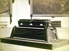 A casket sits on a bier in this black-and-white photo