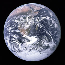 Un disque planétaire de formations nuageuses blanches, brunes et vertes masses terrestres et les océans bleu foncé sur un fond noir. La péninsule arabique, l'Afrique et Madagascar se situent dans la moitié supérieure du disque, tandis que l'Antarctique est au fond.