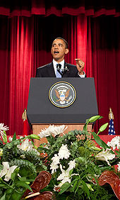 President Obama stands at a podium delivering a speech on