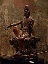 Une sculpture en bois d'une figure bouddhiste assis dans lâches, peint robes.