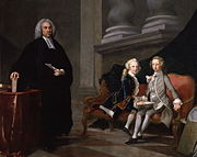 Parte de conversação em óleos: homem vestido de preto com um colarinho clerical está ao lado de dois meninos sentado em um sofá, um vestindo um terno cinza outro um azul. O homem prende uma folha de papel; os meninos segurar um livro.