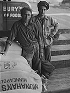 Dois homens que carregaram farinha e um saco de farinha que diz Minneapolis de Monahan e um caminhão Pillsbury