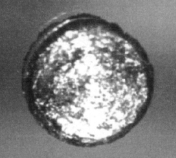 Um pequeno disco de metal prateado, ampliada para mostrar a sua textura metálica