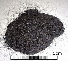Uma pequena pilha de grãos pretos uniformes menores do que 1 mm de diâmetro.