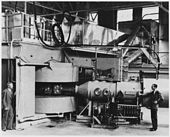 Imagem em preto-e-branco de máquinas pesadas, com dois operadores sentado de lado