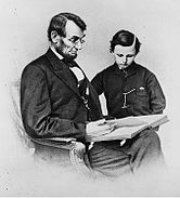 A Lincoln sentado segurando um livro como seu filho olha para ele