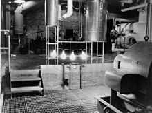 Um quarto industrial com quatro grandes lâmpadas iluminados pendurado em um bar.