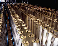 A photo of a large hall filled with arrays of long white standing cylinders.