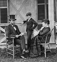 President Grant and family pose in an informal portrait outside. Grant is seated to the left and his wife Julia is seated to the right. Their son Jesse is standing between Grant and Julia.