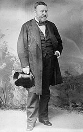 Grant is standing in a civilian dress suit holding a top hat after the Civil War.