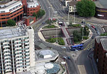 Vista aérea da rotunda, uma junção de várias ruas. Veículos percorrer em torno da rotunda, que é cercada por edifícios, principalmente de vários andares