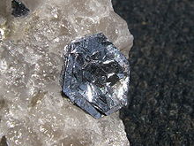 Lustrosa, prateadas, liso, cristais hexagonais em camadas mais ou menos paralelas sentar flowerlike em um áspero pedaço cristalino, translúcido de quartzo.