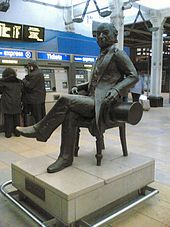A black statue of a seated man holding a top hat.